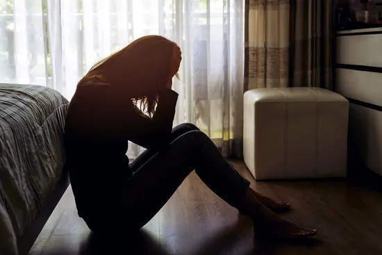 photo of depressed woman in dark bedroom