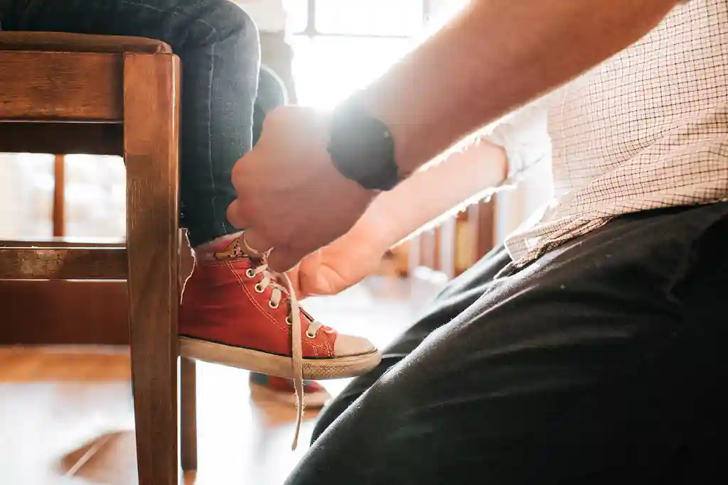 photo of father tying young son's shoes