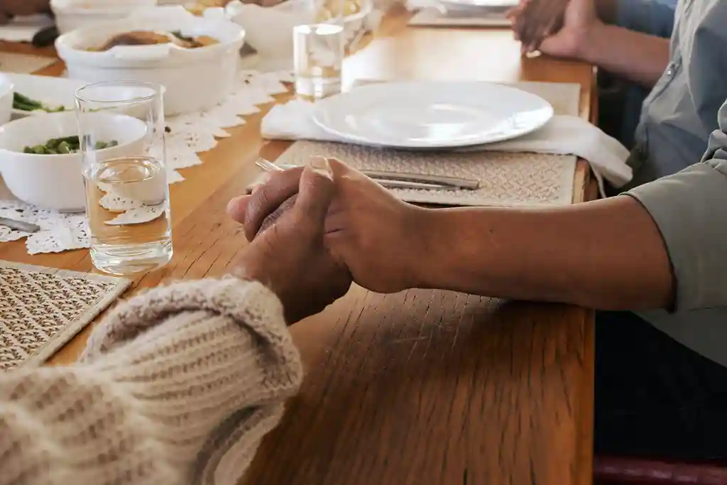 photo of family sitting at table holding hands
