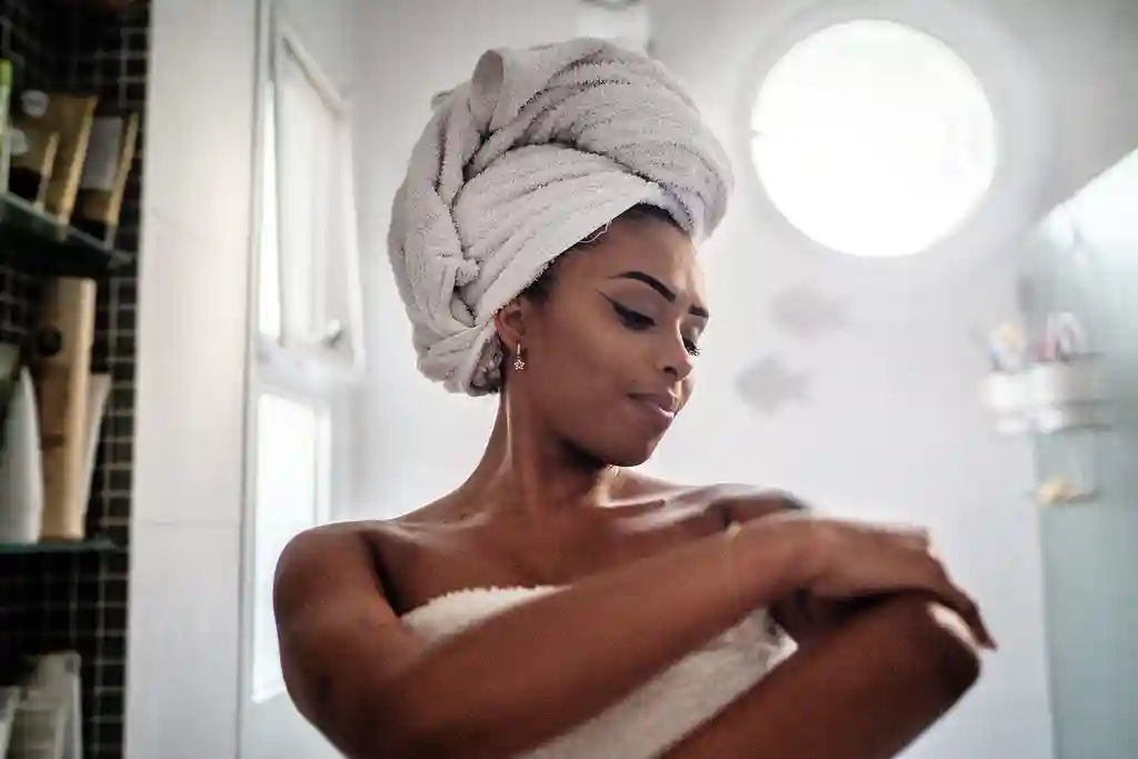 photo of young woman applying moisturizer