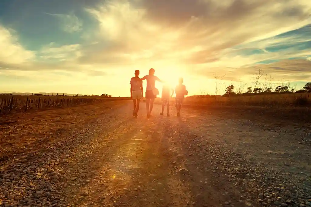 photo of mother with kids walking on country road