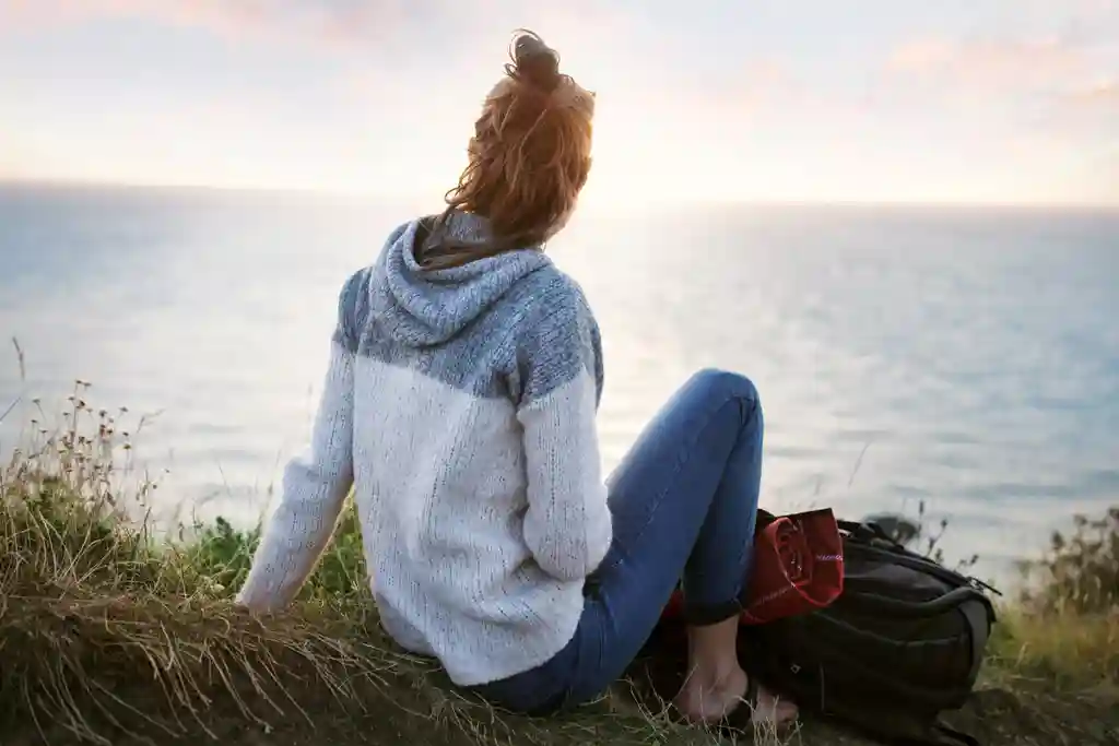photo of girl sitting on edge of cliff