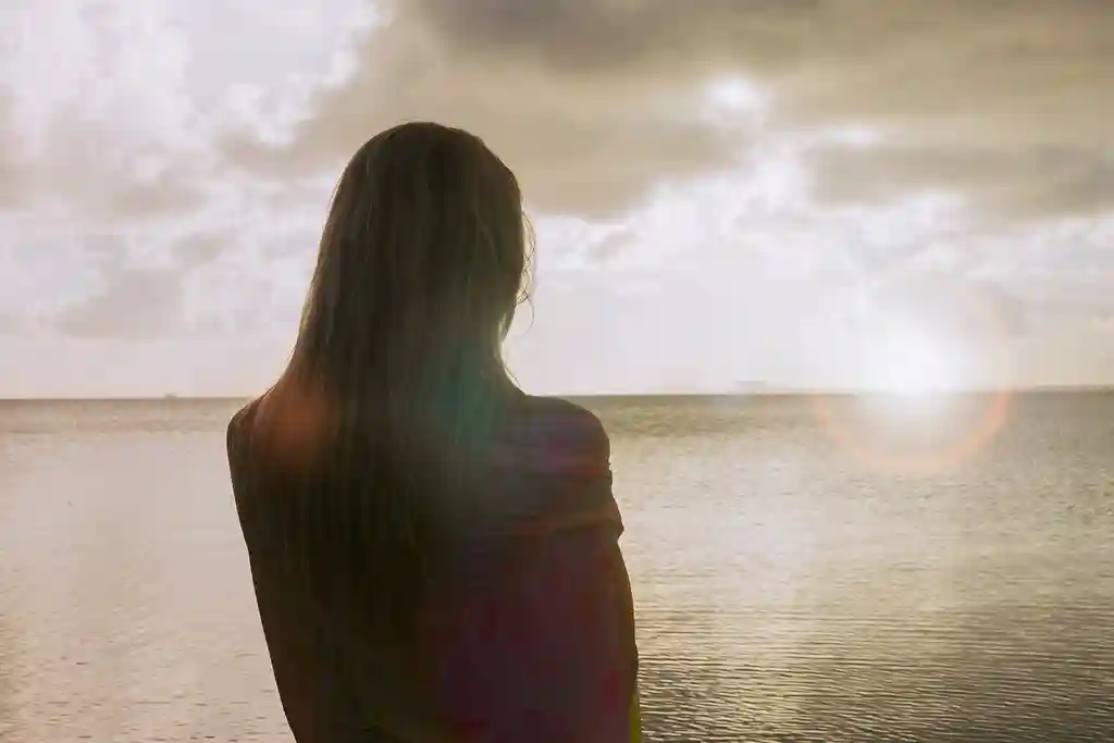 photo of woman on the beach looking at the horizon