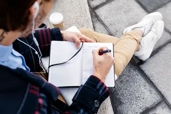 photo of man sitting outside taking notes