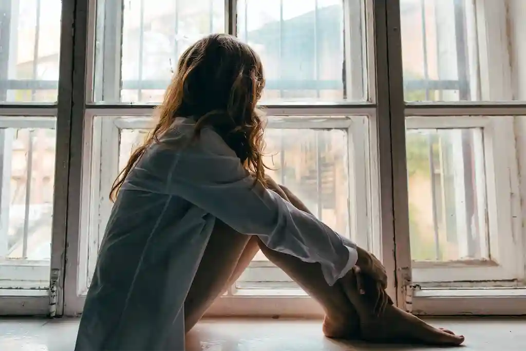 photo of young woman looking throuth window