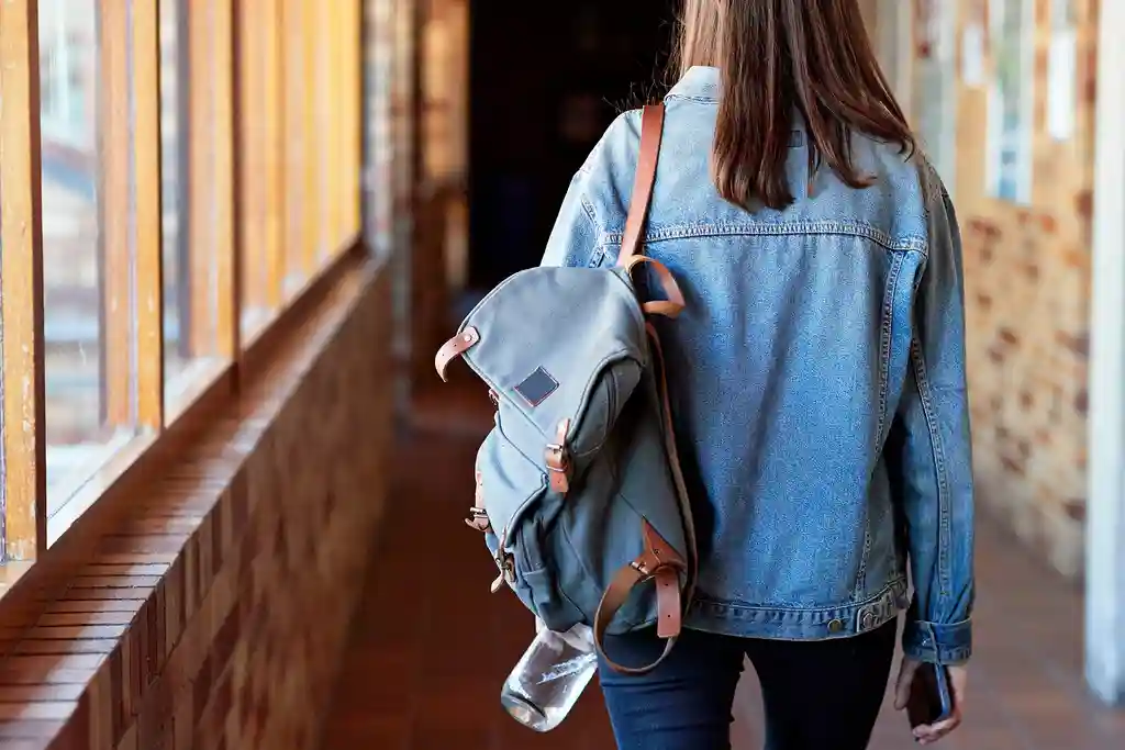 photo of young woman with backpack walking in corr