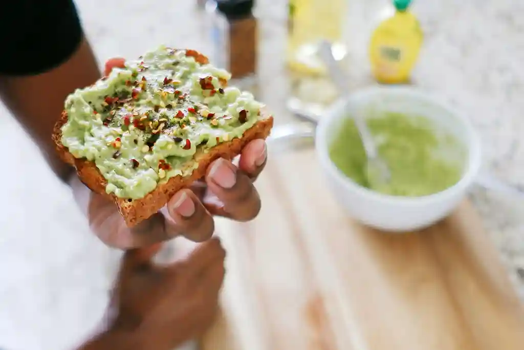 photo of woman eating a slice of avocado toast