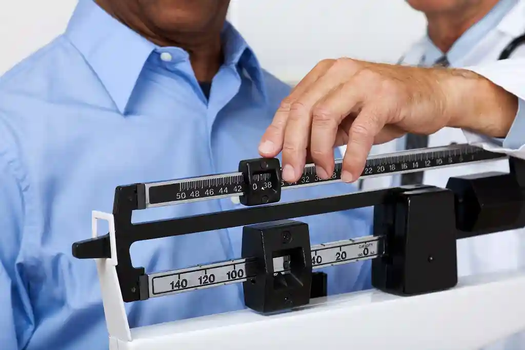 man getting weighed by doctor