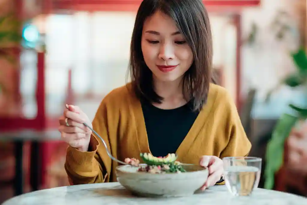 photo of young woman eating salad at restaurant