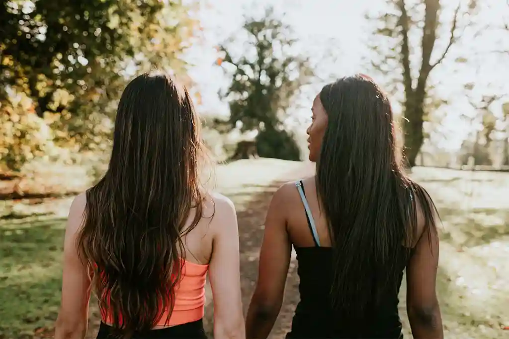 photo of two women walking in the park