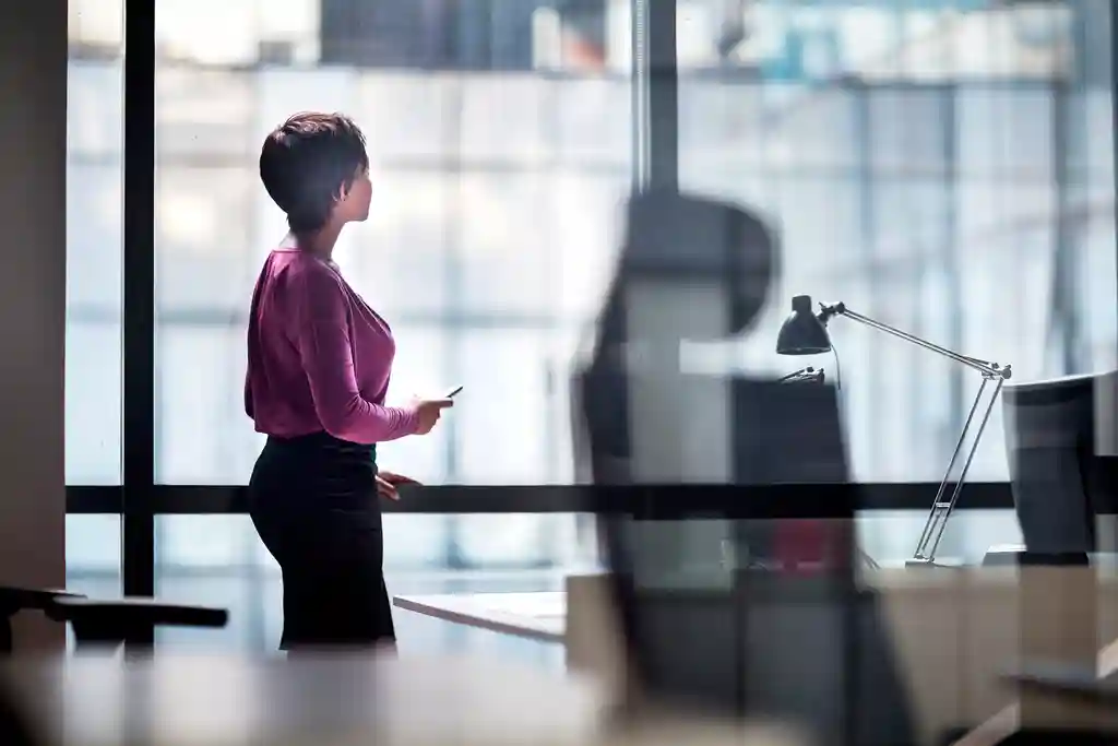 photo of woman looking out window in office