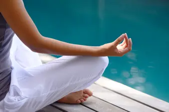 photo of woman meditating by the pool