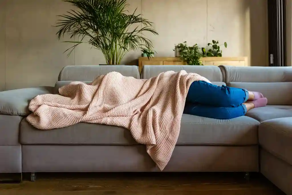 photo of woman sleeping under blanket on sofa