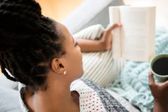 photo of woman reading book and drinking coffee