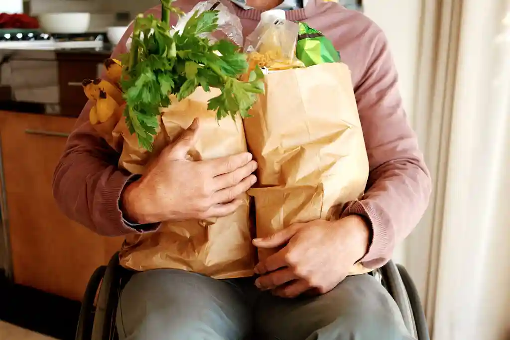 photo of man sitting in wheelchair with groceries
