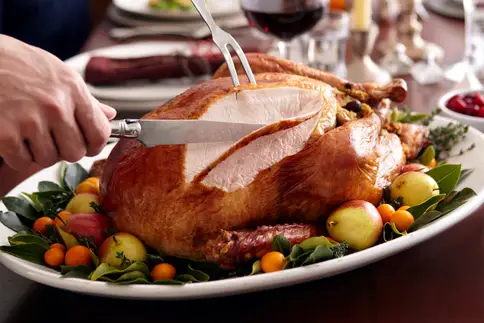 photo of man carving turkey during holiday meal