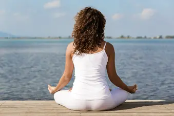 photo of woman holding yoga pose by lake