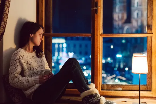 photo of woman looking out window at night