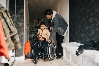 photo of father helping child in wheelchair