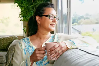 photo of woman having cup of cvffee on sofa