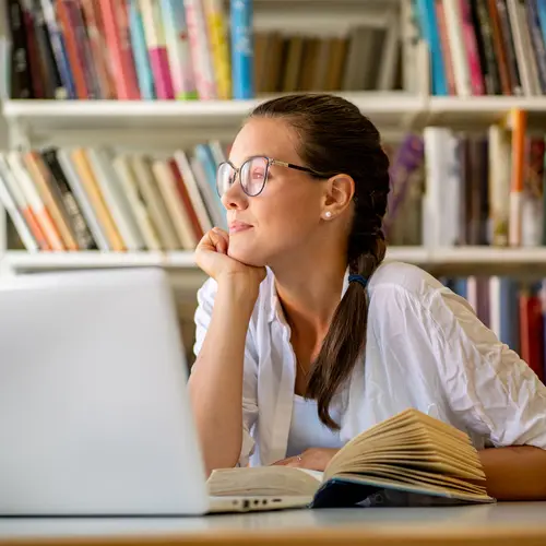 photo of woman looking out window while studying