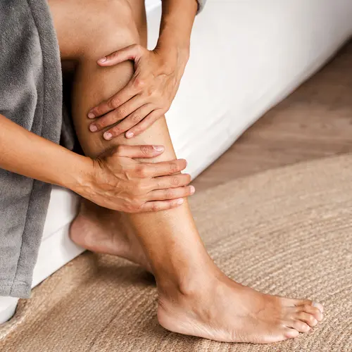 photo of woman massaging sore leg