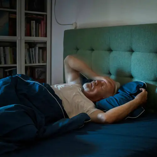 photo of man with insomnia lying in bed