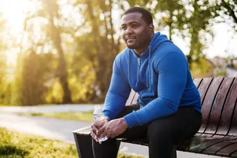 photo of man resting on bench with bottle of water