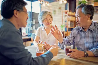 mature friends drinking coffee in cafe