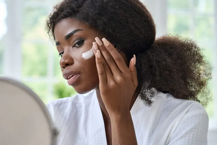 photo of woman applying facial moisturizer