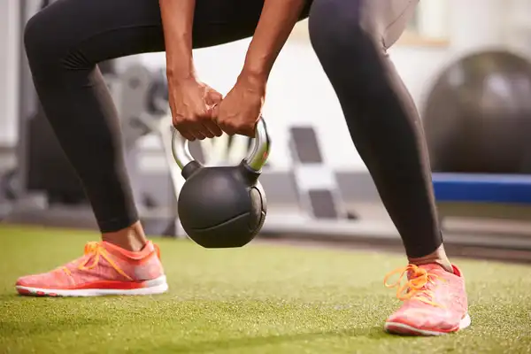 photo of woman exercising with kettlebell weight