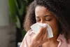 photo of woman sneezing into napkin