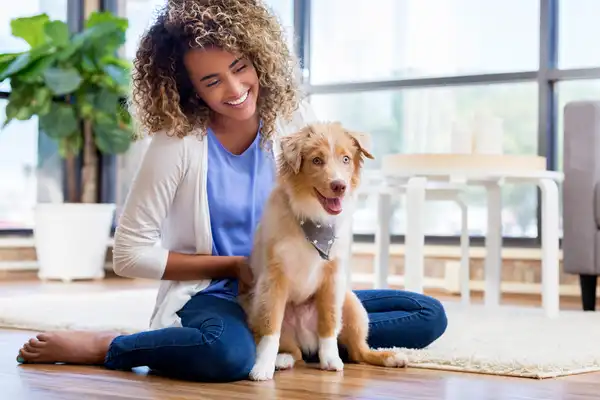 photo of young woman playing with dog