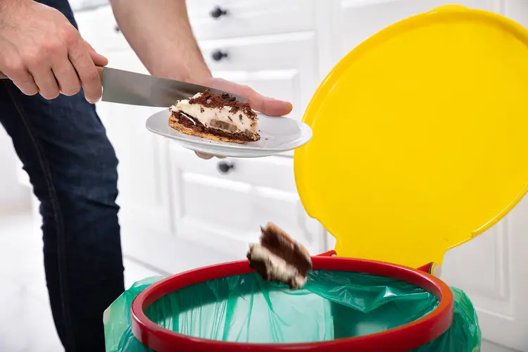 photo of disposing of cake in kitchen trash can