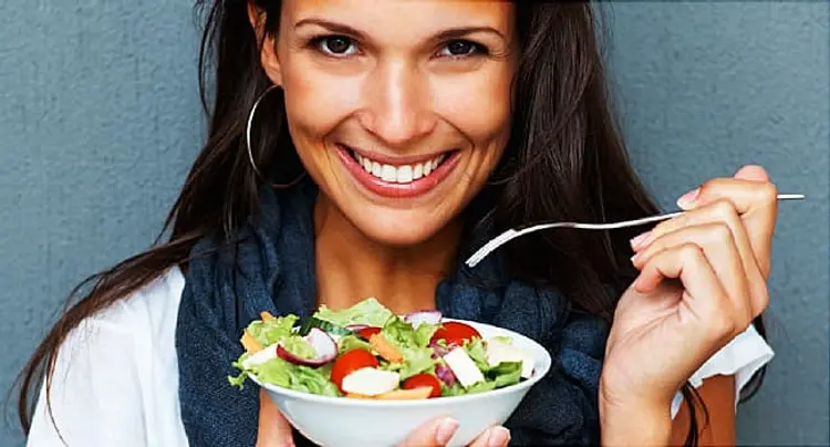 woman smiling while holding bowl of salad