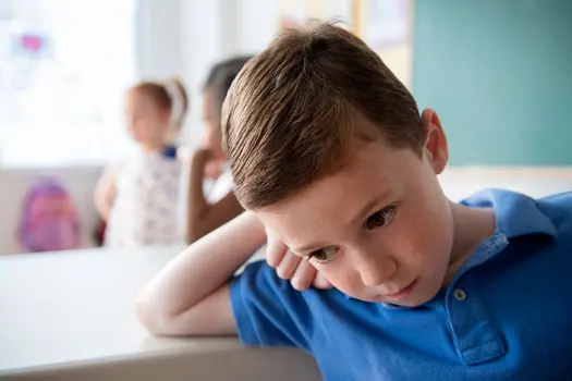 photo of sad young boy in school