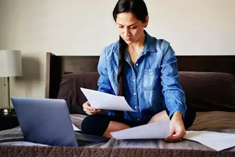 photo of woman reviewing medical paperwork on bed