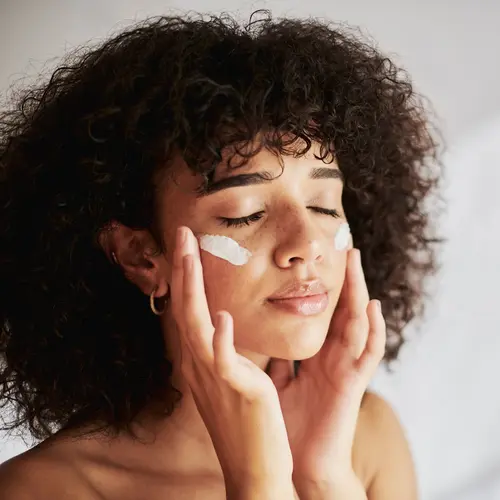 photo of woman applying cream to face