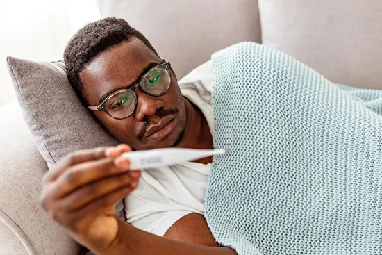 photo of man with fever checking thermometer