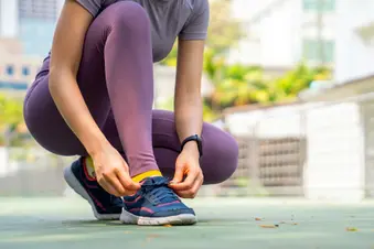 photo of woman tying athletic shoe before workout