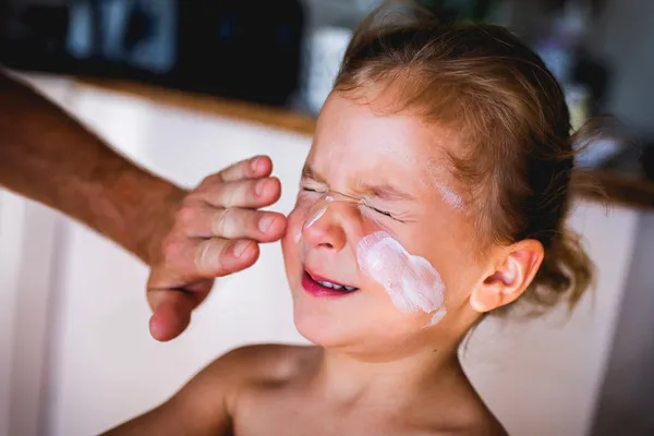 applying sunscreen on boys face